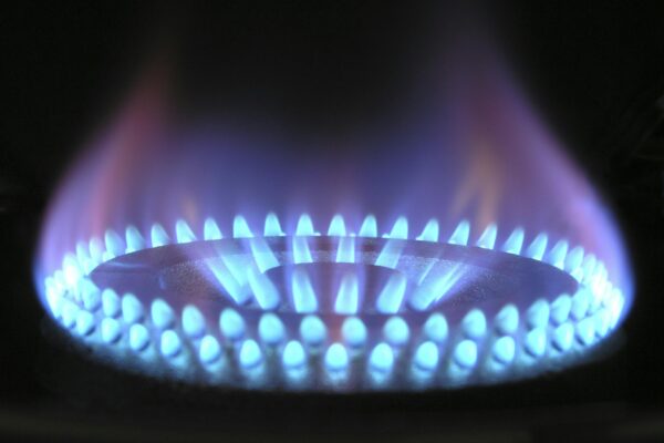 Close-up of a gas stove burner displaying a vibrant blue flame, signifying efficient combustion and energy use for cooking or heating.